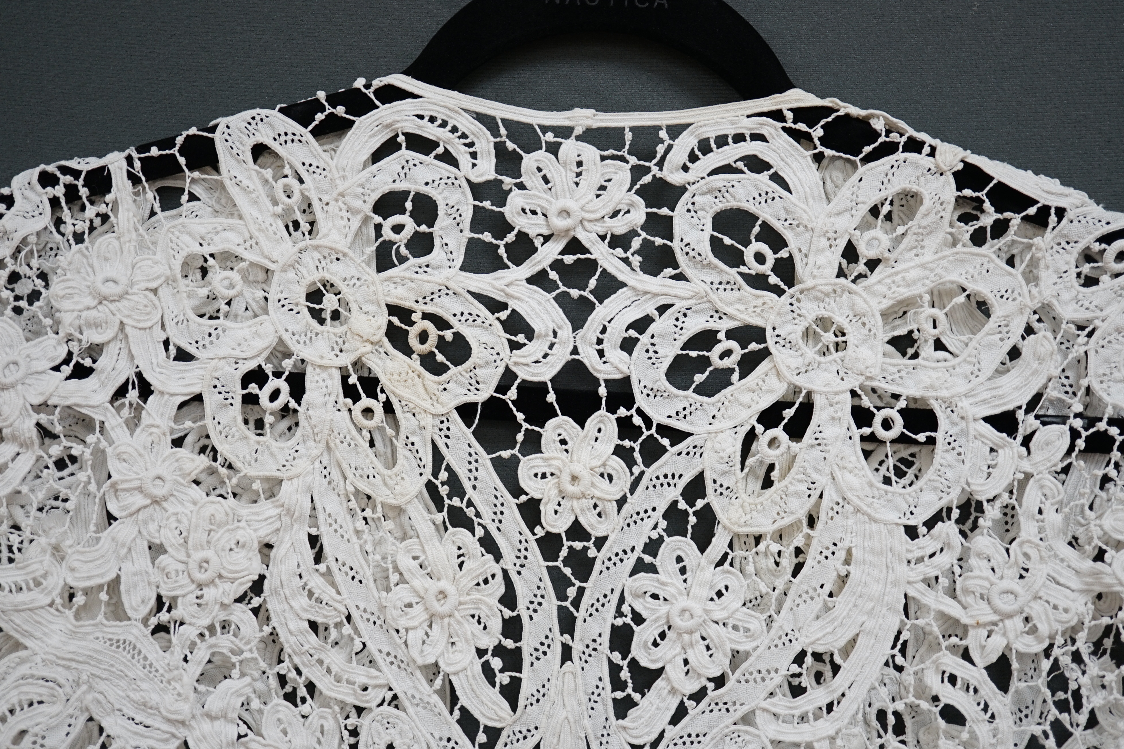 An Edwardian ladies white lace bolero, a tape lace Edwardian cap sleeve bolero with hand sewn bracts, attaching the tape lace together, possibly part of a wedding dress or summer dress, back under arm width 36cm. Conditi